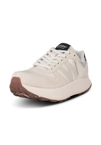 Baskets beige en tissu suédé et mesh, avec des lacets blancs, une semelle extérieure en caoutchouc texturé, et un logo de marque noir sur la languette et le talon.