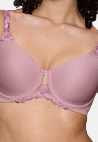 Lichtroze bh van textuurstof, met bloemige kantafwerking en een kleine decoratieve accent in het midden. Verstelbare schouderbanden en gladde cups.