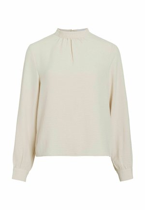 Blouse beige clair à manches longues avec un col montant, une finition froncée au niveau du col et des poignets élastiqués. Texture lisse et design minimaliste.