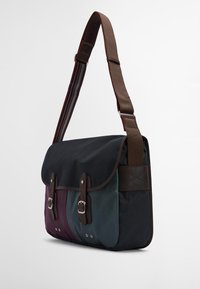 Mala de mensageiro em tecido escuro com um degradé de roxo, azul-petróleo e preto. Apresenta alças e elementos em couro castanho, além de uma alça de ombro ajustável.