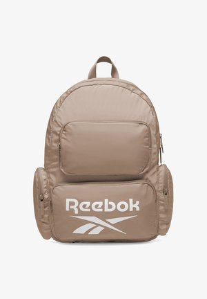 Zaino beige Reebok con ampia tasca frontale, due tasche laterali con zip e logo Reebok bianco sulla tasca frontale inferiore.