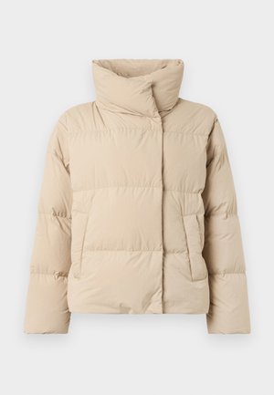 Bezs színű puffertakaró magas gallérral, steppelt mintával, két oldalsó zsebbel és enyhén oversized fazonnal. Simább, matt felület.