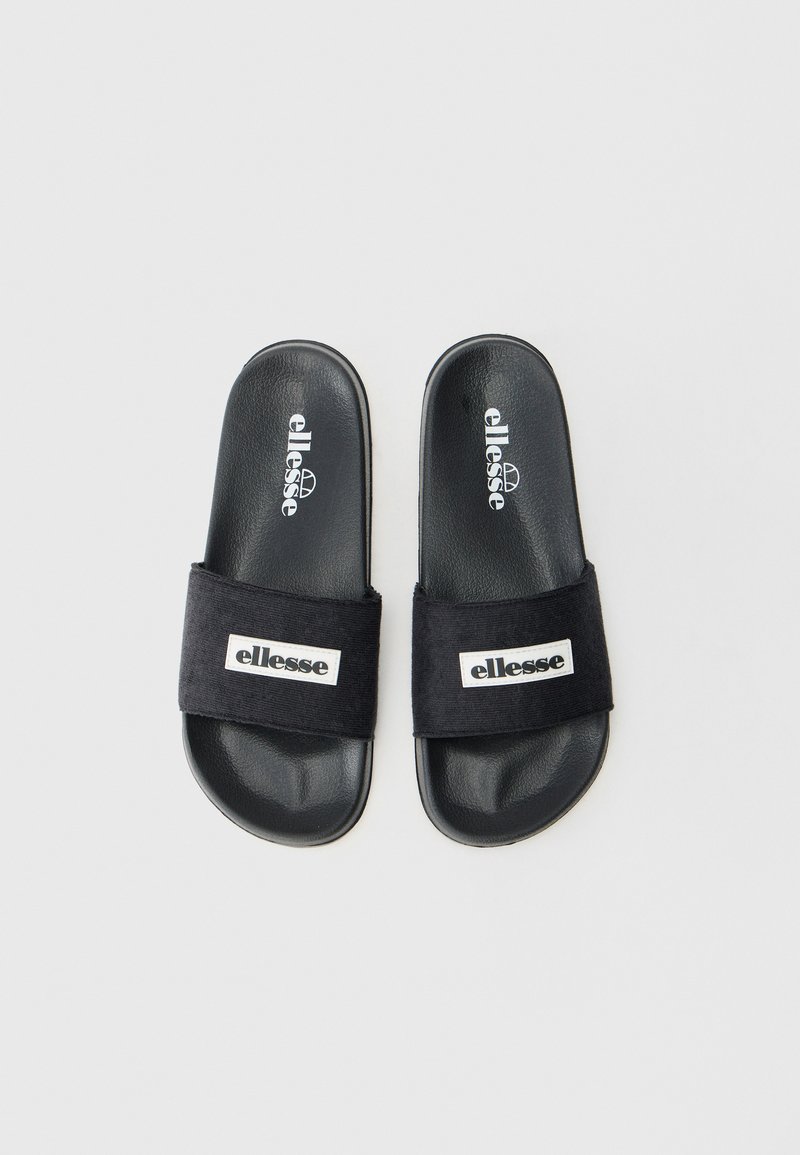 Czarne klapki z gładką syntetyczną podeszwą, szerokim czarnym paskiem z tkaniny z białą łatą z logo z przodu. Szczegóły o fakturowanej powierzchni.