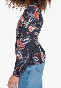 Blusa con motivo floreale, maniche lunghe, fondo blu scuro e fiori vivaci rosa e gialli. Tessuto morbido con vestibilità rilassata.