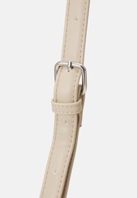 Bežový kožený pásek se stříbrně tónovanou kovovou přezkou a dekoračními nýty. Hladký povrch s prošíváním podél okrajů.