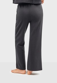 Dunkelgraue weite Hose aus weichem Stoff mit elastischem Bund, die eine glatte Textur und einen sauberen Saum am Knöchel aufweist.