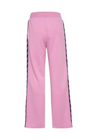 Różowe spodnie o szerokich nogawkach z elastycznym paskiem i ciemnymi bocznymi paskami z plecionym wzorem, widziane od tyłu.