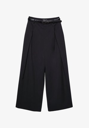 Pantalon noir ample et court avec des plis sur le devant et une fine ceinture noire avec une boucle argentée à la taille.