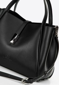 Bolso de cuero negro con forma estructurada, dos asas y correa desmontable. Presenta un cierre de hardware plateado brillante y un logo embellecido.