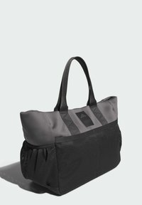 Čierna a sivá taška tote má mäkký vrch s vystuženými rukoväťami, sieťovanú dolnú časť a obdĺžnikovú nášivku s logom na prednej strane.