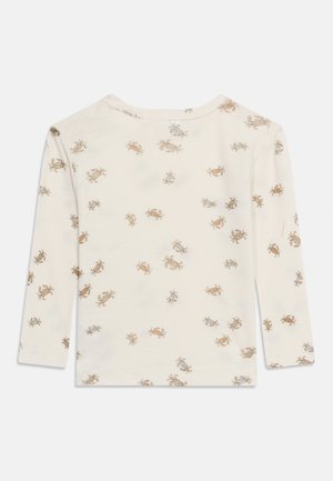 Košulja dugih rukava krem boje s malim plavim i smeđim printom raka rasprostranjenim po tkanini, prikazana sa stražnje strane.