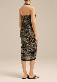 Czarna i biała halterka w wzór paisley, wykonana z lekkiego materiału, dopasowana u góry i zwężająca się do kolan, z prostym wykończeniem.