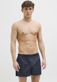 Shorts de bain pour homme gris foncé avec une taille élastique, fabriqués en matériau léger, présentant un design simple et une coupe décontractée.