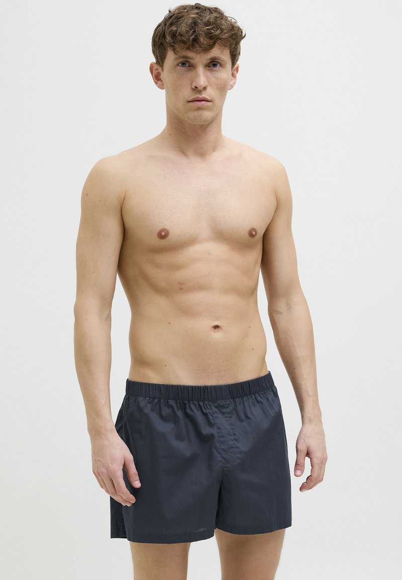 Shorts de bain pour homme gris foncé avec une taille élastique, fabriqués en matériau léger, présentant un design simple et une coupe décontractée.
