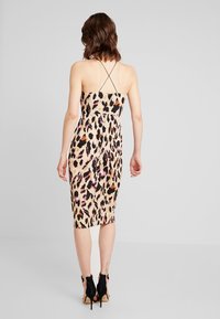 Leopard print midi dress with thin crisscross straps, a fitted silhouette, and soft fabric. Color palette includes pink, black, and beige.