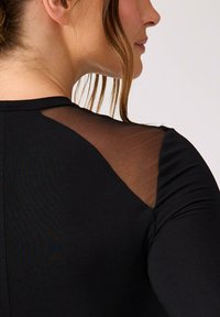 Czarny dopasowany top z przezroczystymi siateczkowymi ramionami, okrągłym dekoltem i długimi rękawami, o gładkiej fakturze i bezszwowym designie.