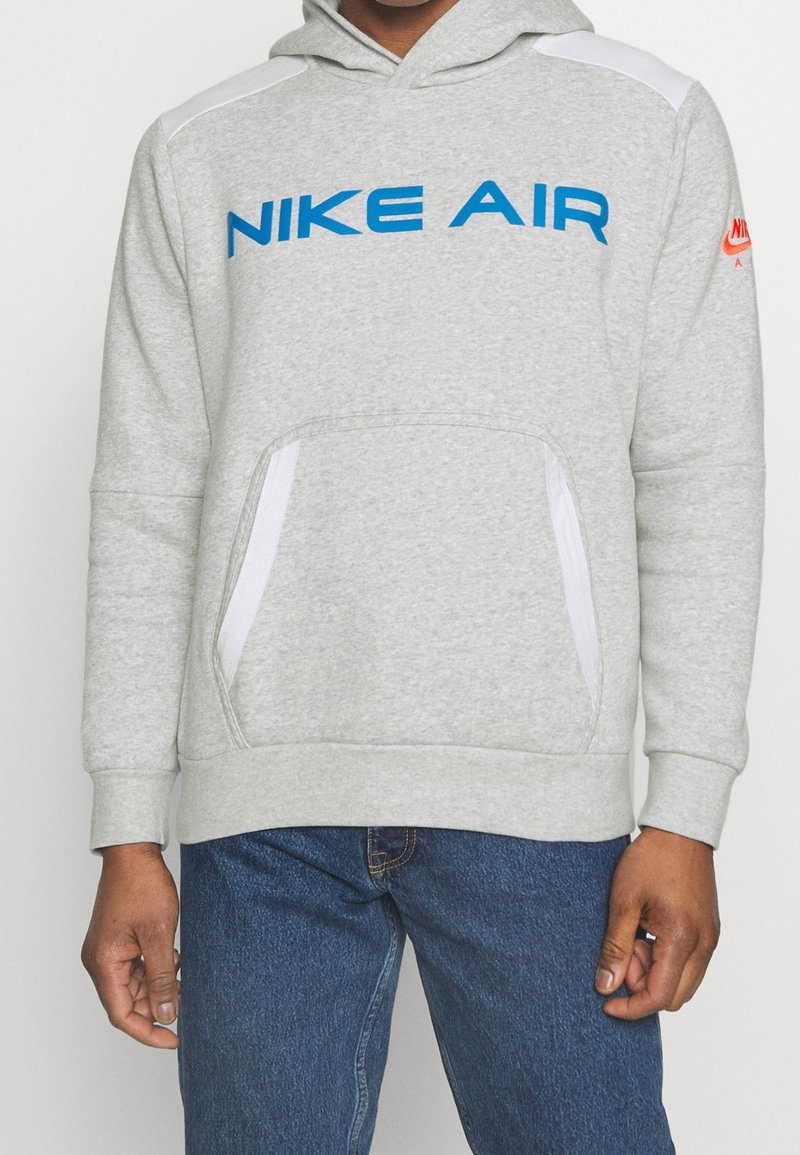 Gray hoodie with blue "NIKE AIR" text, white shoulder accents, and front kangaroo pocket. Made of soft fabric with ribbed cuffs and hem.