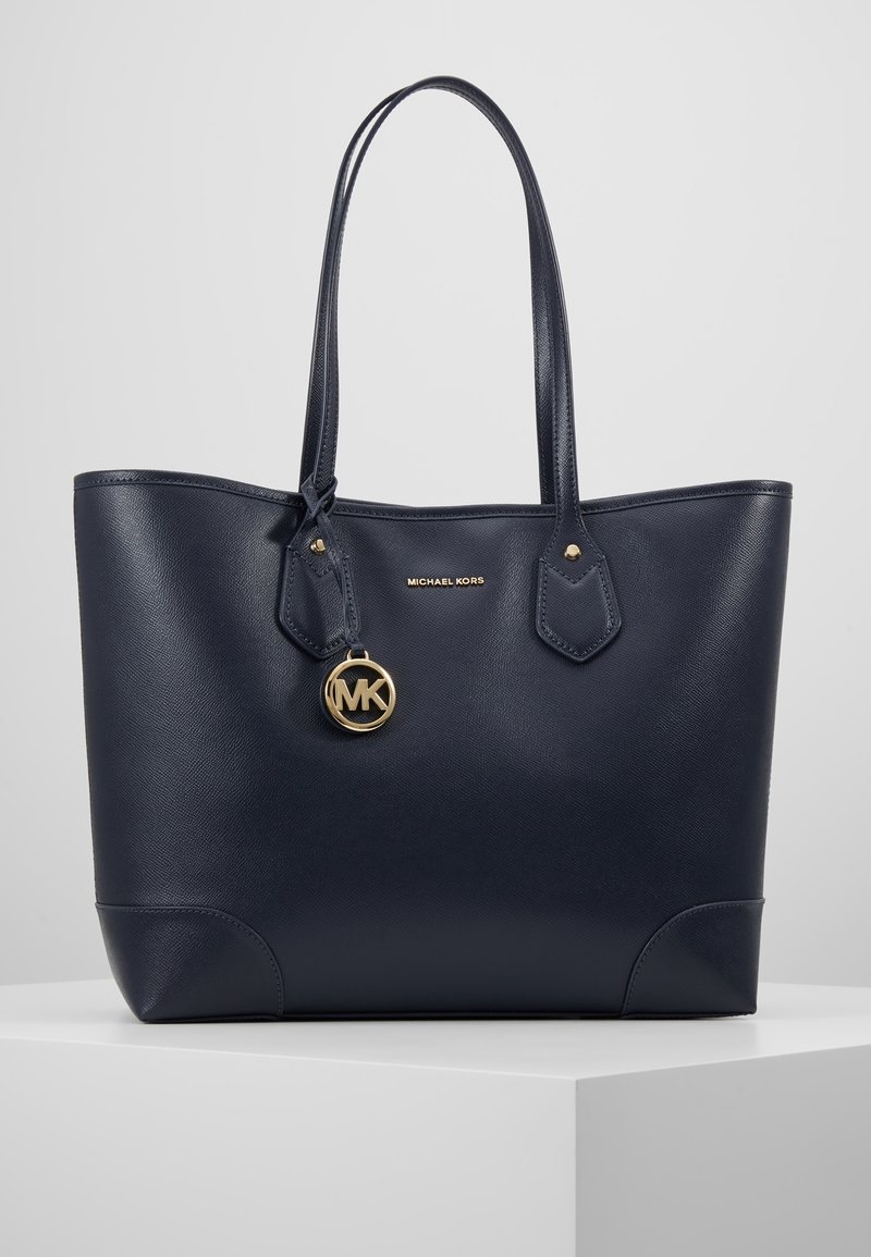 Sac cabas en cuir bleu marine Michael Kors avec deux anses d'épaule et un porte-clés doré en forme de logo MK suspendu près du centre supérieur.