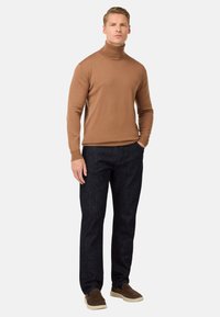 Rjav turtleneck pulover v kombinaciji s temnimi denim jeans. Pulover ima oprijet kroj, medtem ko so hlače s straight-leg krojem in temnim pranjem.