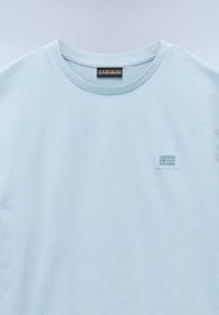Lichtblauwe katoenen t-shirt met ronde hals, voorzien van een klein geborduurd logo op de linkerborst. Glad textuur, casual design.