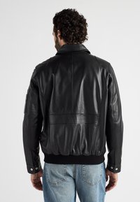 Schwarze Leder-Bomberjacke mit geripptem Saum, Druckknopfärmeln und glatter Oberfläche mit dezenten Nähdetails.