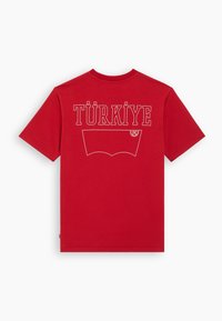 Camiseta roja de manga corta con "TÜRKİYE" y un gráfico del logo de Levi's en blanco contorneado en la parte posterior.