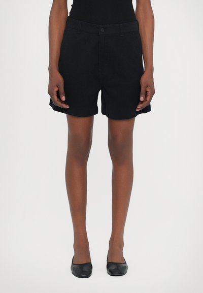Shorts en coton noirs de coupe classique, avec une fermeture à bouton et des poignets retournés. Texture lisse et détails de design minimalistes.