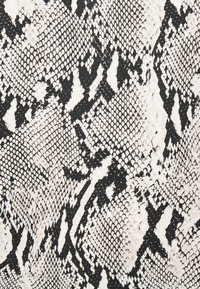Μαύρο και άσπρο σχέδιο από δέρμα φιδιού με ακανόνιστα λέπια και ποικίλα σχήματα που δημιουργούν μια υφή παρόμοια με αυτή ερπετού.