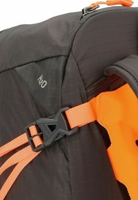 Schwarzer Stoffrucksack mit H2O-Etikett, ausgestattet mit einem orangefarbenen Gurt und einer Schnalle. Strukturierte Oberfläche mit sichtbaren Nähten und strapazierfähigen Materialien.