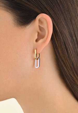 Boucles d'oreilles en métal doré et argenté en forme de trombones, présentant un design géométrique avec une texture lisse et des couleurs combinées.