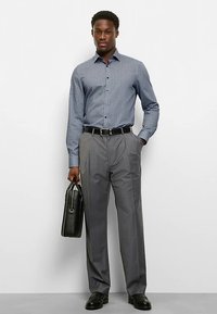Gray checkered button-up shirt paired with gray dress pants. Black belt and shoes. Holding a black leather briefcase. Smooth texture, tailored fit.