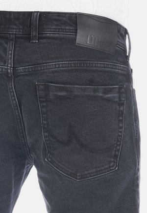 Jeans di denim neri con una patta in pelle sul punto vita, cuciture sulla tasca posteriore e un classico design a cinque tasche.