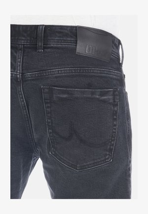 Jeans di denim neri con una patta in pelle sul punto vita, cuciture sulla tasca posteriore e un classico design a cinque tasche.