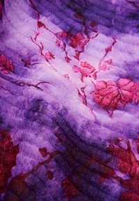 Tissu violet avec une texture légère, présentant un motif floral de roses roses et des lignes ondulées superposées. Un éclat subtil renforce la profondeur visuelle.