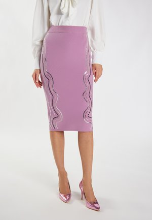 Gonna a tubo rosa aderente con accenti ondulati in paillettes argentate e nere. Abbinata a scarpe con tacco alta e lucide di colore rosa. Tessuto texturizzato.