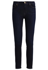 Slim-fit tmavě modré džíny se předními kapsami, zapínáním na knoflík a poutky na opasek, zobrazené na bílém pozadí.