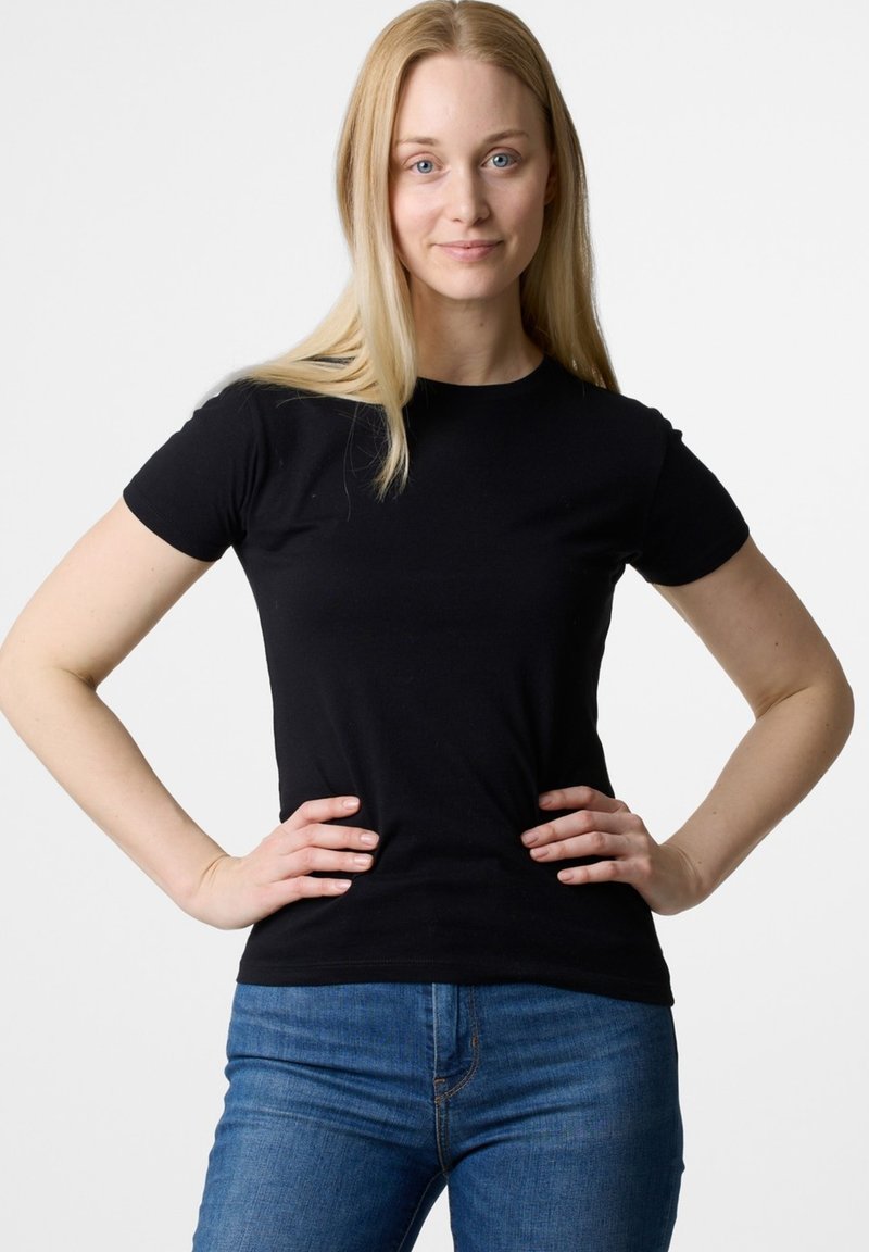 Czarna koszulka krótki rękaw z miękkiej tkaniny, dopasowany krój, okrągły dekolt, noszona z niebieskimi dżinsami. Gładka faktura, brak widocznych wzorów.