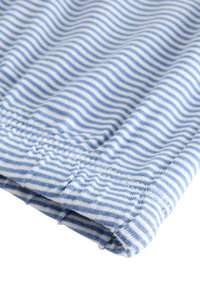 Blau-weißer gestreifter Stoff mit einer weichen Textur, der eine gefaltete Kante und sichtbare Nähdetails aufweist.