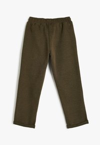 Braune, weiche Stoffhosen mit einem elastischen Bund, schmal zulaufenden Beinen und hochgekrempelten Säumen. Entworfen für Komfort und Bewegungsfreiheit.