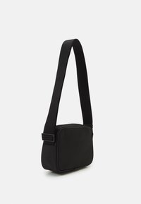 Borsa a spalla in tessuto nero con forma rettangolare, design piatto, tracolla regolabile e aspetto minimalista. Presenta una texture liscia.