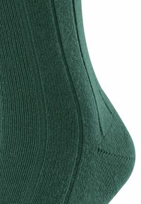 Calcetín verde acanalado con un acabado texturizado, contorno moldeado y talón reforzado. El material parece suave y elástico con líneas verticales definidas.