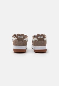Hnědé semišové tenisky s bílými akcenty a logem VANS na patě. Disponují texturovaným povrchem a podešví z gumy. Zaoblený límec designu.