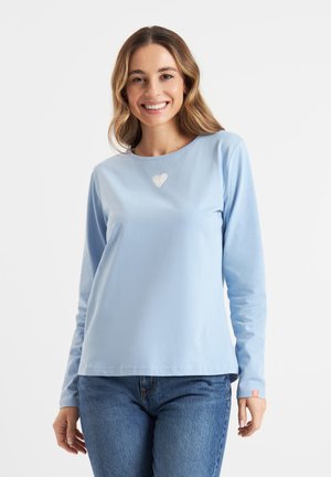 Lichtblauwe langesleeve t-shirt van zachte stof met een hartvormig design op de borst. Heeft een ronde halslijn en een rechte zoom.