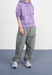 Ljuslila bomullshoodie med krage och känguruficka, i kombination med löst sittande olivgröna cargobyxor och beiga sneakers.