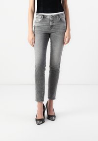 Gray denim skinny jeans with a high waist, five pockets, and a slightly faded finish, paired with black high-heeled shoes.