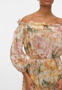 Robe à motif floral avec décolleté à volants dénudé sur les épaules, manches bouffantes et taille à nouer. Confectionnée dans un tissu léger et doux aux couleurs pastel.