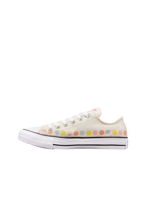 Zapatillas de lona en color crema, con patrones florales multicolores a lo largo del costado, cordones blancos y suelas de goma negras.
