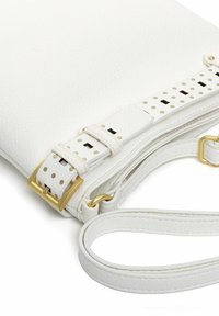 Valge nahast ristihoidik, millel on tekstuuriga viimistlus, kuldsed detailid ning reguleeritav rihm, millel on täpiline muster ja pandla detail.