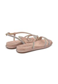 Sandalias beige con correas brillantes, suela plana y una hebilla circular. La plantilla parece suave, con un sutil estampado de la marca.