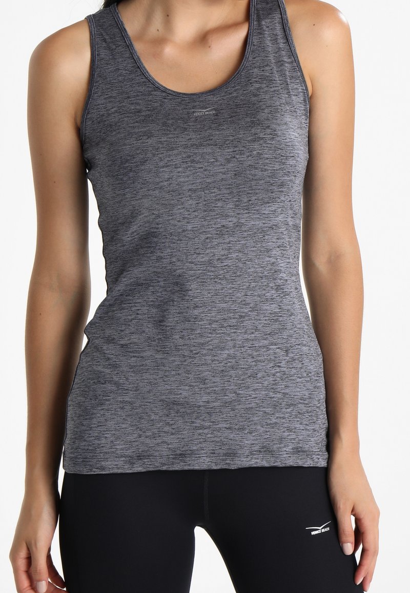 Canottiera sportiva grigia senza maniche con una sottile consistenza melangiata, design aderente e dettaglio del logo vicino al colletto. Abbinata a leggings neri.